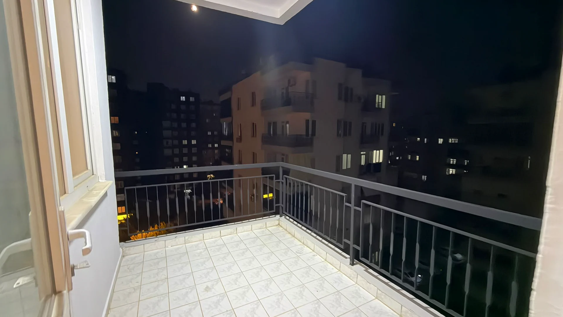 Balcony floor, railings and surrounding buildings at night